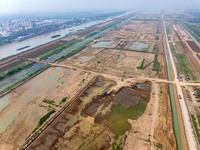 Excavators and trucks work in the river channel at the construction site of the second phase of the Huaihe River Waterway into the sea in Hu...