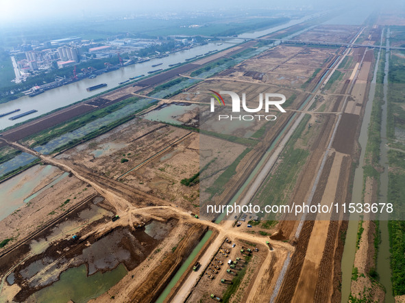 Excavators and trucks work in the river channel at the construction site of the second phase of the Huaihe River Waterway into the sea in Hu...