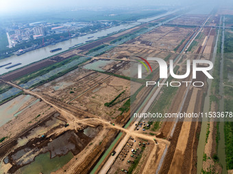 Excavators and trucks work in the river channel at the construction site of the second phase of the Huaihe River Waterway into the sea in Hu...