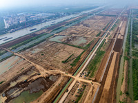 Excavators and trucks work in the river channel at the construction site of the second phase of the Huaihe River Waterway into the sea in Hu...