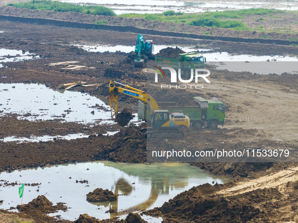 Excavators and trucks work in the river channel at the construction site of the second phase of the Huaihe River Waterway into the sea in Hu...