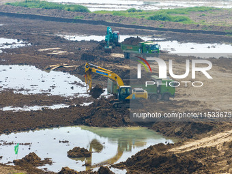 Excavators and trucks work in the river channel at the construction site of the second phase of the Huaihe River Waterway into the sea in Hu...