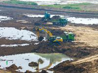 Excavators and trucks work in the river channel at the construction site of the second phase of the Huaihe River Waterway into the sea in Hu...