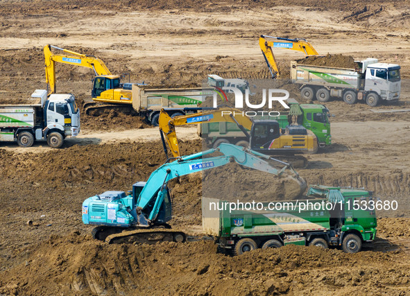 Excavators and trucks work in the river channel at the construction site of the second phase of the Huaihe River Waterway into the sea in Hu...