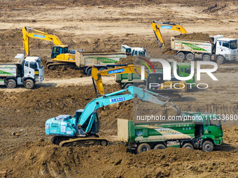 Excavators and trucks work in the river channel at the construction site of the second phase of the Huaihe River Waterway into the sea in Hu...