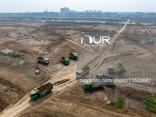 Excavators and trucks work in the river channel at the construction site of the second phase of the Huaihe River Waterway into the sea in Hu...