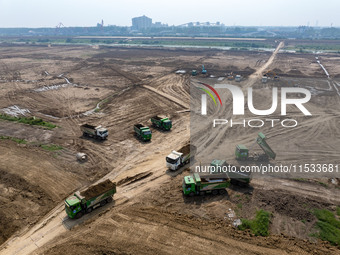 Excavators and trucks work in the river channel at the construction site of the second phase of the Huaihe River Waterway into the sea in Hu...