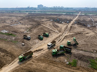 Excavators and trucks work in the river channel at the construction site of the second phase of the Huaihe River Waterway into the sea in Hu...