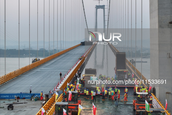 Workers spread asphalt on the deck of the main bridge of the Longtan Yangtze River Bridge in Yangzhou, China, on September 1, 2024. 