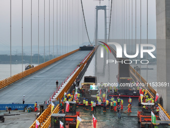 Workers spread asphalt on the deck of the main bridge of the Longtan Yangtze River Bridge in Yangzhou, China, on September 1, 2024. (