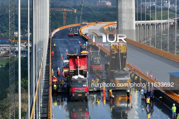 Workers spread asphalt on the deck of the main bridge of the Longtan Yangtze River Bridge in Yangzhou, China, on September 1, 2024. 