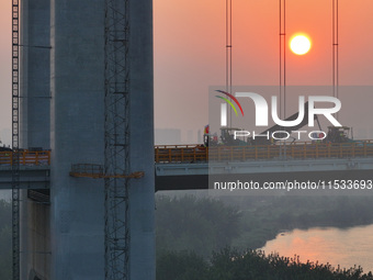 Workers spread asphalt on the deck of the main bridge of the Longtan Yangtze River Bridge in Yangzhou, China, on September 1, 2024. (