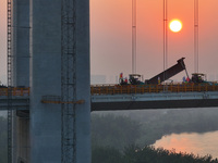 Workers spread asphalt on the deck of the main bridge of the Longtan Yangtze River Bridge in Yangzhou, China, on September 1, 2024. (