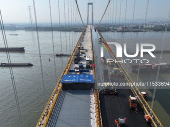 Workers spread asphalt on the deck of the main bridge of the Longtan Yangtze River Bridge in Yangzhou, China, on September 1, 2024. (