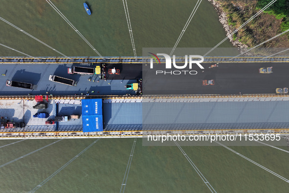 Workers spread asphalt on the deck of the main bridge of the Longtan Yangtze River Bridge in Yangzhou, China, on September 1, 2024. 