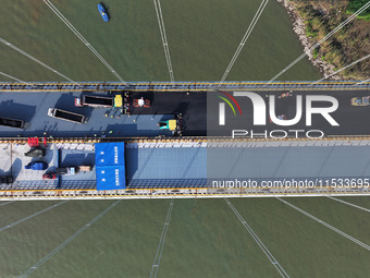 Workers spread asphalt on the deck of the main bridge of the Longtan Yangtze River Bridge in Yangzhou, China, on September 1, 2024. (