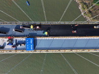 Workers spread asphalt on the deck of the main bridge of the Longtan Yangtze River Bridge in Yangzhou, China, on September 1, 2024. (