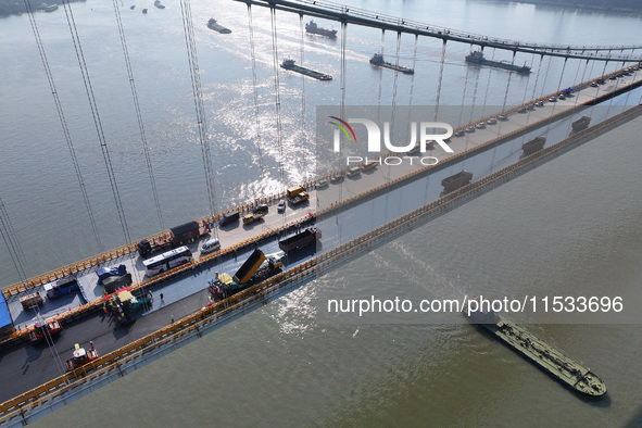 Workers spread asphalt on the deck of the main bridge of the Longtan Yangtze River Bridge in Yangzhou, China, on September 1, 2024. 