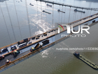 Workers spread asphalt on the deck of the main bridge of the Longtan Yangtze River Bridge in Yangzhou, China, on September 1, 2024. (