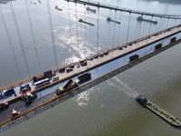 Workers spread asphalt on the deck of the main bridge of the Longtan Yangtze River Bridge in Yangzhou, China, on September 1, 2024. (