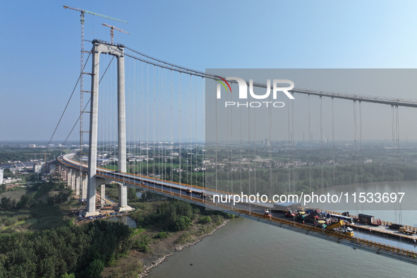 Workers spread asphalt on the deck of the main bridge of the Longtan Yangtze River Bridge in Yangzhou, China, on September 1, 2024. 