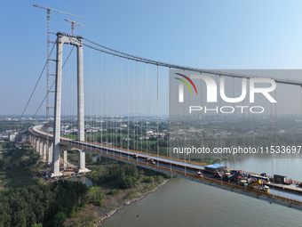 Workers spread asphalt on the deck of the main bridge of the Longtan Yangtze River Bridge in Yangzhou, China, on September 1, 2024. (