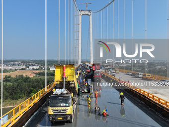 Workers spread asphalt on the deck of the main bridge of the Longtan Yangtze River Bridge in Yangzhou, China, on September 1, 2024. (