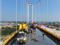 Workers spread asphalt on the deck of the main bridge of the Longtan Yangtze River Bridge in Yangzhou, China, on September 1, 2024. (