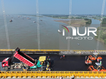 Workers spread asphalt on the deck of the main bridge of the Longtan Yangtze River Bridge in Yangzhou, China, on September 1, 2024. (