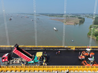 Workers spread asphalt on the deck of the main bridge of the Longtan Yangtze River Bridge in Yangzhou, China, on September 1, 2024. (