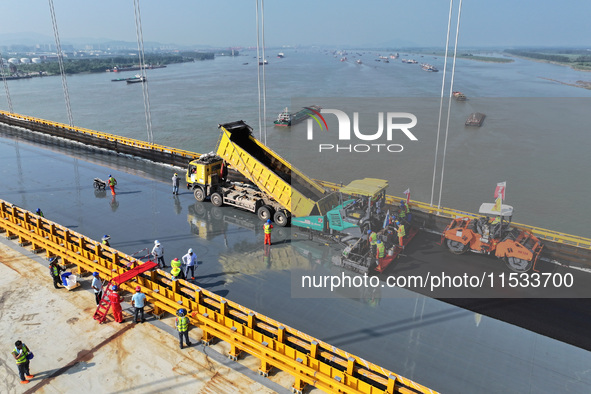 Workers spread asphalt on the deck of the main bridge of the Longtan Yangtze River Bridge in Yangzhou, China, on September 1, 2024. 