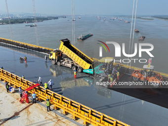 Workers spread asphalt on the deck of the main bridge of the Longtan Yangtze River Bridge in Yangzhou, China, on September 1, 2024. (