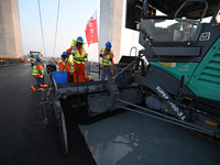 Workers spread asphalt on the deck of the main bridge of the Longtan Yangtze River Bridge in Yangzhou, China, on September 1, 2024. (