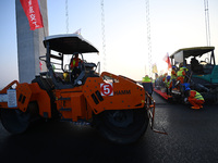 Workers spread asphalt on the deck of the main bridge of the Longtan Yangtze River Bridge in Yangzhou, China, on September 1, 2024. (