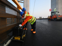 Workers spread asphalt on the deck of the main bridge of the Longtan Yangtze River Bridge in Yangzhou, China, on September 1, 2024. (