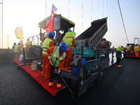 Workers spread asphalt on the deck of the main bridge of the Longtan Yangtze River Bridge in Yangzhou, China, on September 1, 2024. (