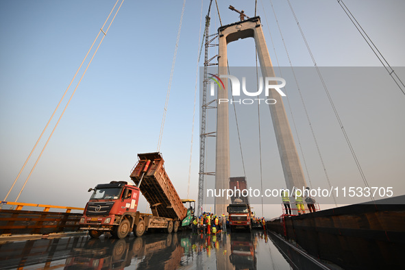 Workers spread asphalt on the deck of the main bridge of the Longtan Yangtze River Bridge in Yangzhou, China, on September 1, 2024. 