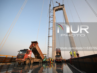 Workers spread asphalt on the deck of the main bridge of the Longtan Yangtze River Bridge in Yangzhou, China, on September 1, 2024. (