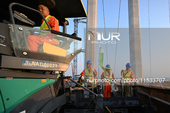 Workers spread asphalt on the deck of the main bridge of the Longtan Yangtze River Bridge in Yangzhou, China, on September 1, 2024. 