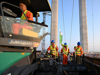 Workers spread asphalt on the deck of the main bridge of the Longtan Yangtze River Bridge in Yangzhou, China, on September 1, 2024. (