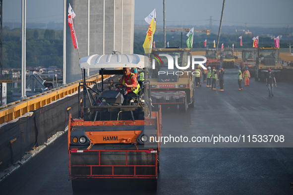 Workers spread asphalt on the deck of the main bridge of the Longtan Yangtze River Bridge in Yangzhou, China, on September 1, 2024. 