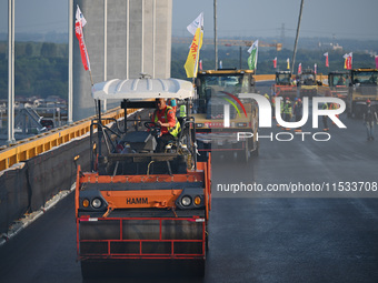 Workers spread asphalt on the deck of the main bridge of the Longtan Yangtze River Bridge in Yangzhou, China, on September 1, 2024. (