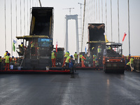 Workers spread asphalt on the deck of the main bridge of the Longtan Yangtze River Bridge in Yangzhou, China, on September 1, 2024. (