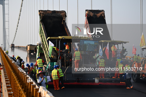 Workers spread asphalt on the deck of the main bridge of the Longtan Yangtze River Bridge in Yangzhou, China, on September 1, 2024. 