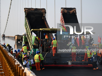 Workers spread asphalt on the deck of the main bridge of the Longtan Yangtze River Bridge in Yangzhou, China, on September 1, 2024. (