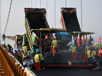 Workers spread asphalt on the deck of the main bridge of the Longtan Yangtze River Bridge in Yangzhou, China, on September 1, 2024. (