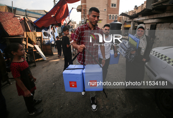 Health workers carry containers filled with polio vaccines during a vaccination campaign in Deir Al-Balah in the central Gaza Strip, on Sept...