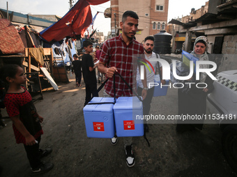 Health workers carry containers filled with polio vaccines during a vaccination campaign in Deir Al-Balah in the central Gaza Strip, on Sept...