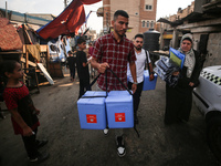 Health workers carry containers filled with polio vaccines during a vaccination campaign in Deir Al-Balah in the central Gaza Strip, on Sept...