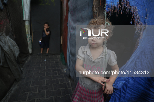 Displaced Palestinian children stand inside a United Nations school sheltering displaced people during a vaccination campaign in Deir Al-Bal...